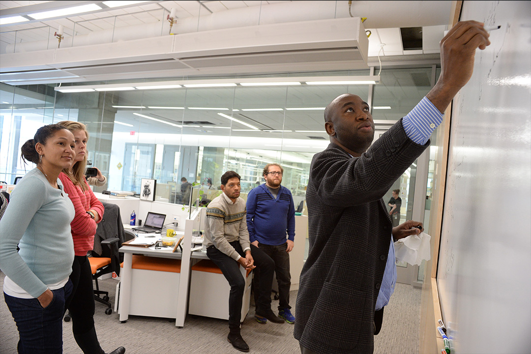 Professor writing on whiteboard teaching engineering management