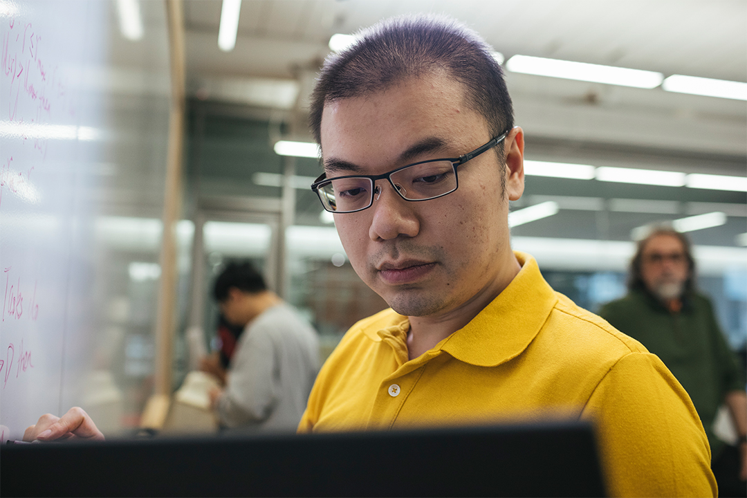 Doctoral student writing on whiteboard in computer engineering lab